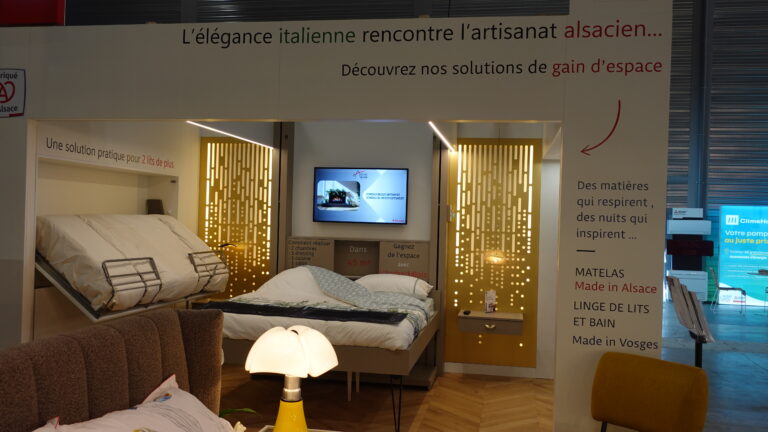 Vue d'une chambre optimisée par l'Arche du Bois : lit superposé fixe, armoire ouverte sur la gauche, lit double escamotable montant au plafond au centre, et télévision intégrée dans le mur. Aménagement intérieur intelligent.