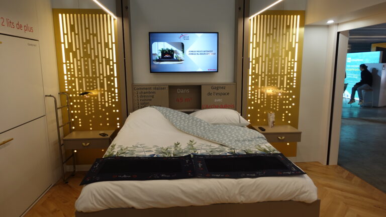 Chambre optimisée avec lit double escamotable montant au plafond, télévision et bibliothèque intégrées, et deux lits armoires fermés sur la gauche. Aménagement intérieur sur mesure par l'Arche du Bois.