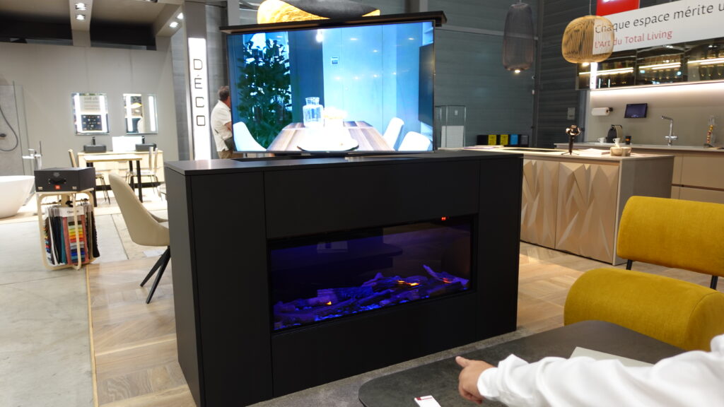 Cheminée décorative à vapeur d'eau avec flammes froides, et télévision escamotable sortie et positionnée au-dessus du foyer. Aménagement mural moderne et sur mesure de l'Arche du Bois.