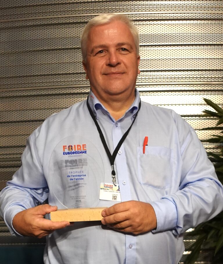 Denis Clément, gérant de l'Arche du Bois, tenant fièrement le Trophée de l'Entreprise de l'Année 2025, lors de la Foire Européenne de Strasbourg. Charpente bois et construction écologique.