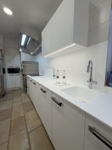 Plan de travail blanc avec éviers intégrés et robinetterie moderne pour une cuisine professionnelle au design minimaliste réalisée pour le projet cuisine Bugatti.