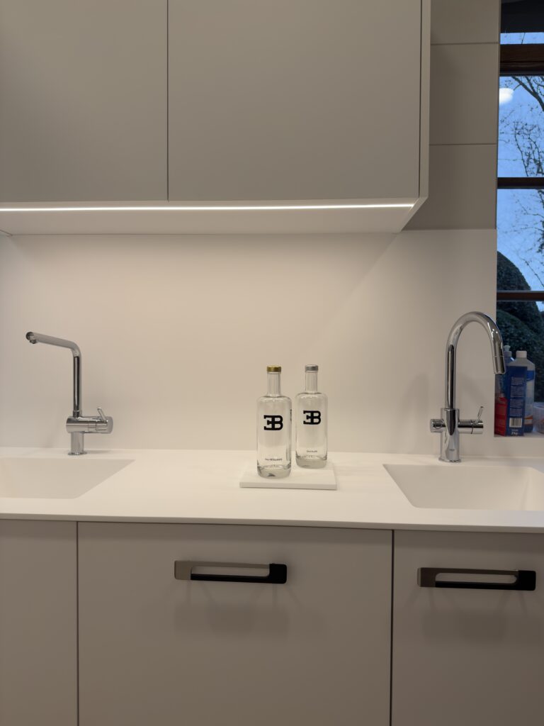 Aménagement d'un double évier intégré dans un plan de travail blanc pour une cuisine professionnelle au design minimaliste, réalisée pour le projet cuisine Bugatti.