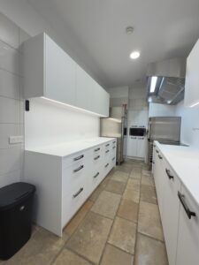 Projet Cuisine professionnelle moderne blanche avec poignées noires, plan de travail épuré et électroménager en inox dans les ateliers Bugatti.