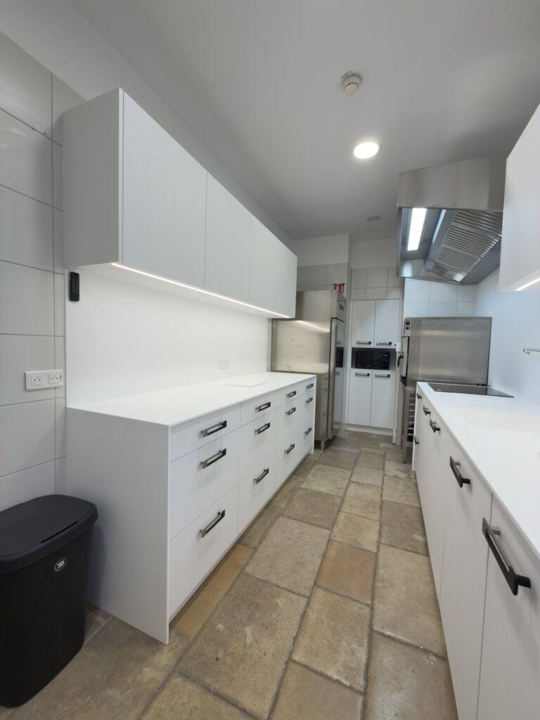 Projet Cuisine professionnelle moderne blanche avec poignées noires, plan de travail épuré et électroménager en inox dans les ateliers Bugatti.