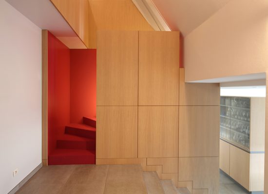 Agencement sur mesure par LDC Agencement – L’Arche du Bois : rangement en bois en face avec escalier rouge derrière.
