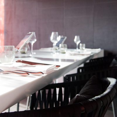 Vue rapprochée de tables et chaises de salle à manger, avec des verres soigneusement disposés sur les plateaux — un agencement raffiné et accueillant signé Arche du Bois, parfait pour un espace de restauration convivial et soigné