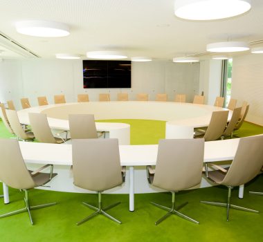 Ensemble de mobilier composé d’un bureau blanc en demi-cercle avec chaise, associé à une table ronde avec assise assortie