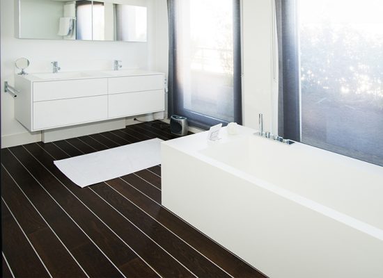 Salle de bain sur mesure par LDC Agencement – L’Arche du Bois : baignoire centrale, meuble vasque double à gauche avec miroir en dessous, design contemporain et agencement personnalisé.