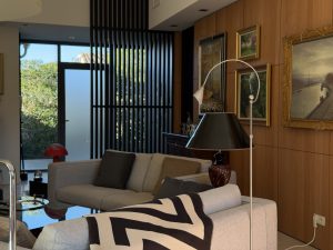 Agencement sur mesure dans un salon contemporain (projet particulier) par L'Arche du Bois. Un habillage mural en hêtre chaleureux accueille des tableaux d'art , tandis qu'un claustra en bois sombre structure l'agencement intérieur avec élégance.