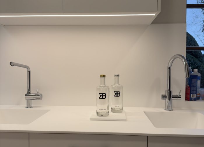 Aménagement d'un double évier intégré dans un plan de travail blanc pour une cuisine professionnelle au design minimaliste, réalisée pour le projet cuisine Bugatti.