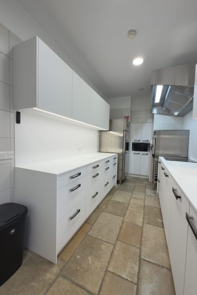 Aménagement complet d'une cuisine professionnelle au design minimaliste avec mobilier blanc sur mesure pour le projet cuisine Bugatti.