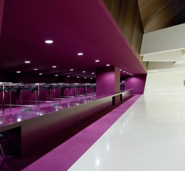 Salle avec un mur blanc sur la droite et un comptoir d’accueil violet sur la gauche