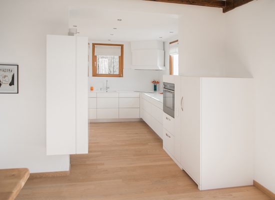 Cuisine au design blanc épuré avec meubles et murs blancs, contrastée par un sol en parquet bois naturel — un agencement sobre et élégant réalisé par Arche du Bois.