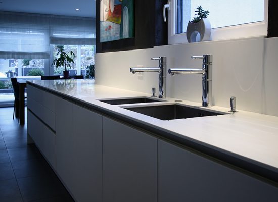 Salle de bain sur mesure par LDC Agencement – L’Arche du Bois : deux lavabos avec robinets, placards en dessous, fenêtre en arrière-plan et portes avec vitrage au fond.